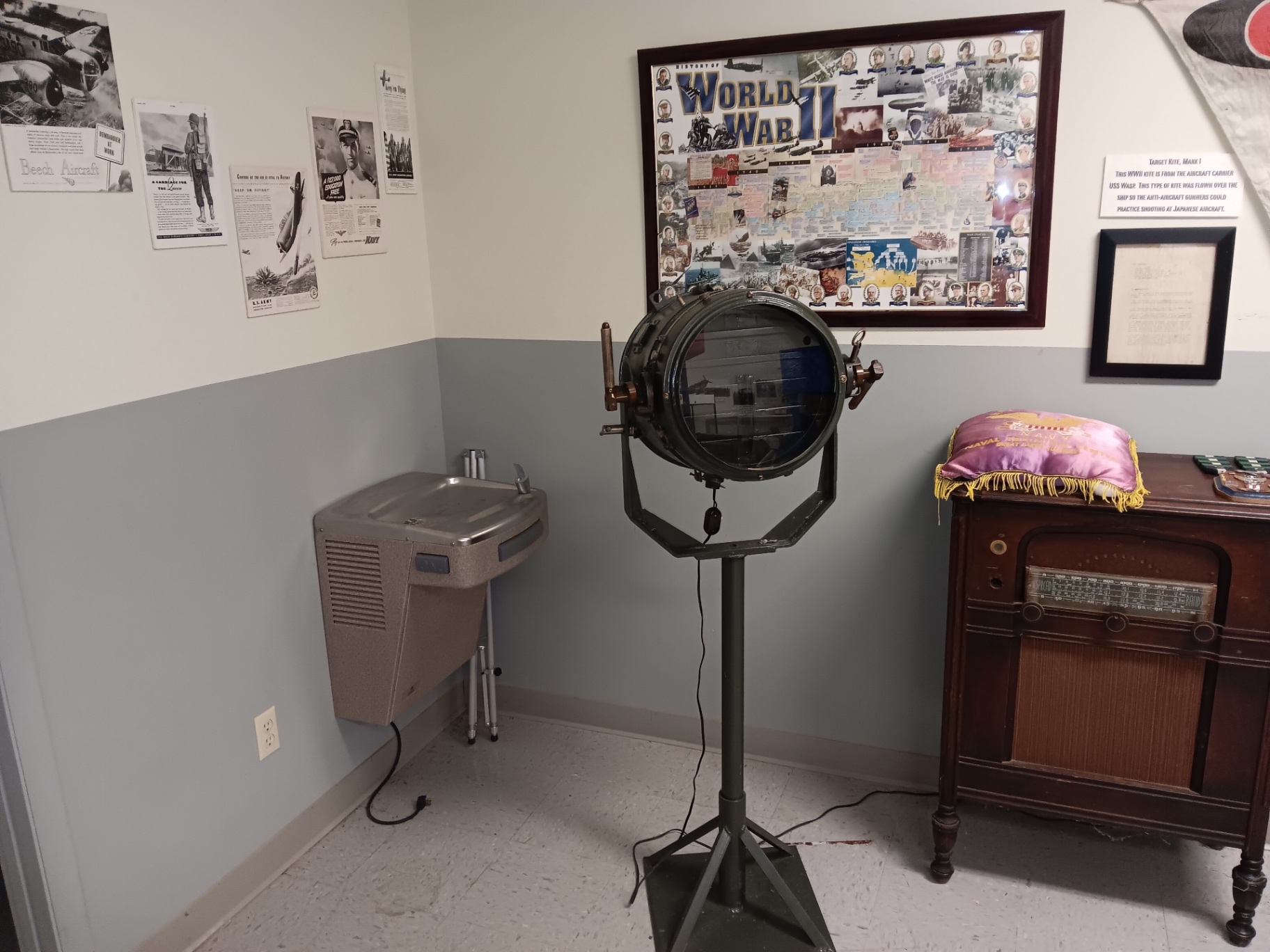 The WWII corner: a history-of-the-war board, a naval signal lamp off a warship, and a period console radio.