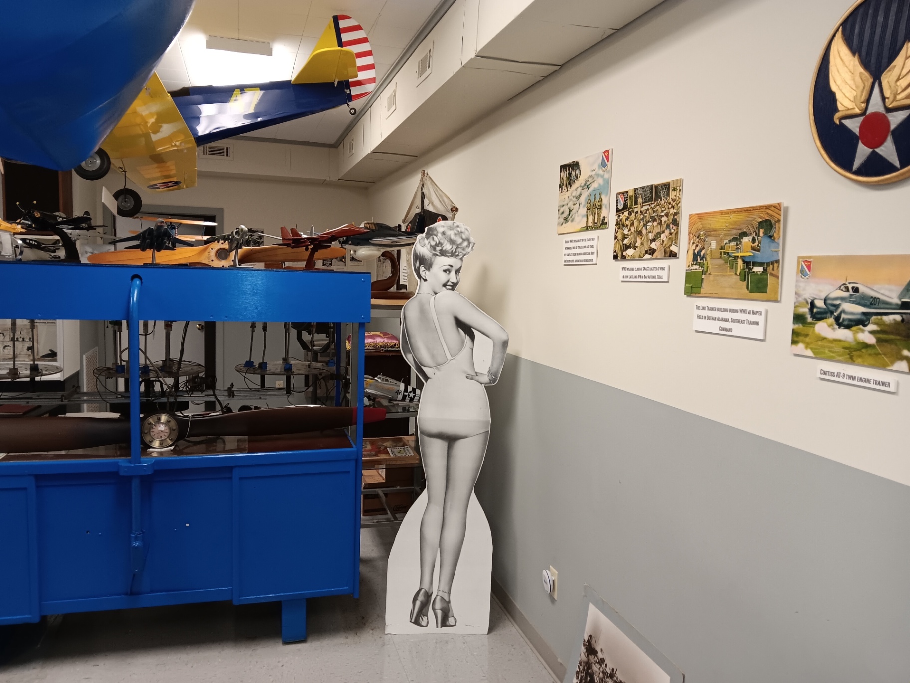A wartime pin-up cutout, hand-built model aircraft, and the WWII pre-flight training wall.