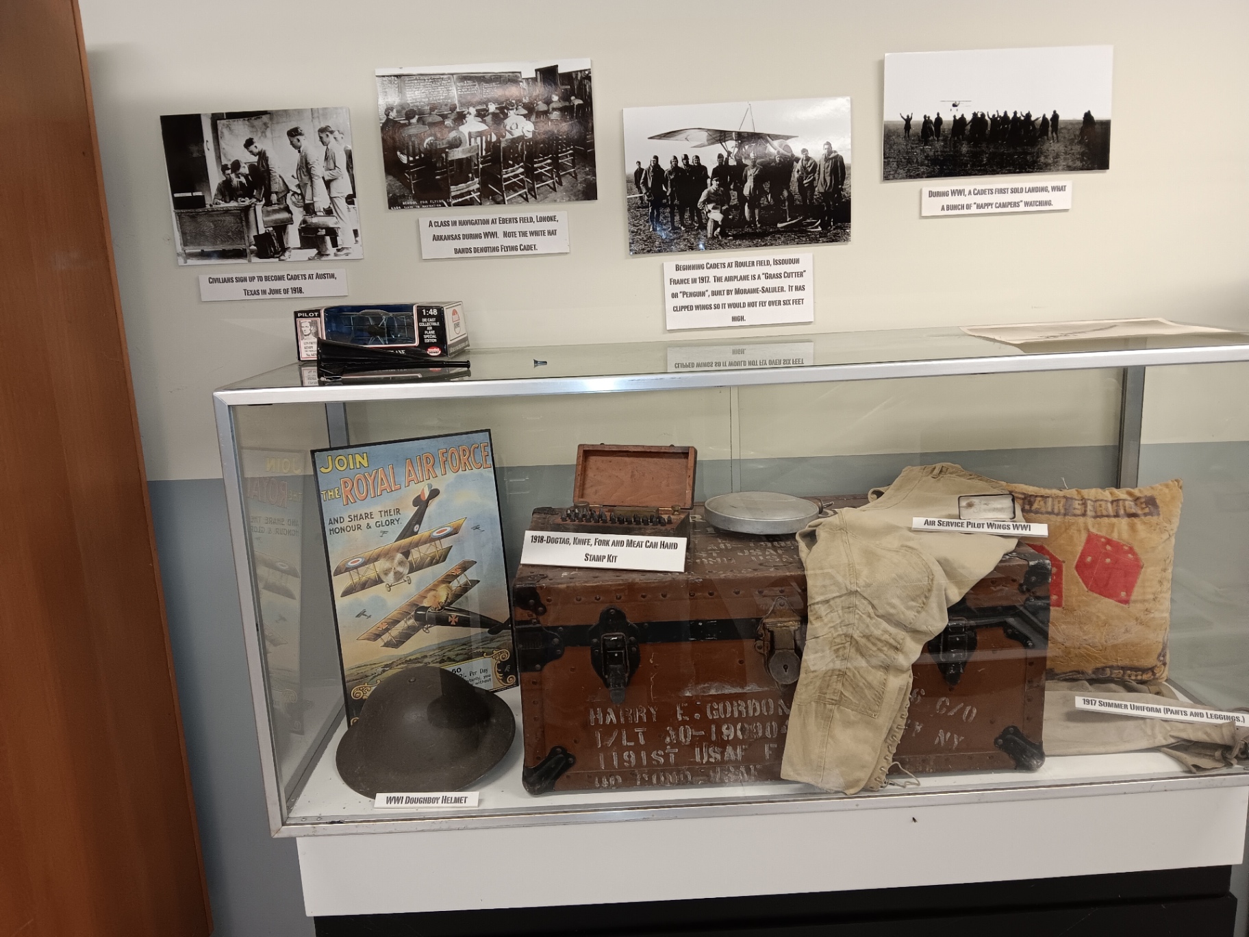 WWI cadet gear — a 1918 footlocker, doughboy helmet, dogtag and mess kit, 1917 summer uniform and a Royal Air Force recruiting poster.