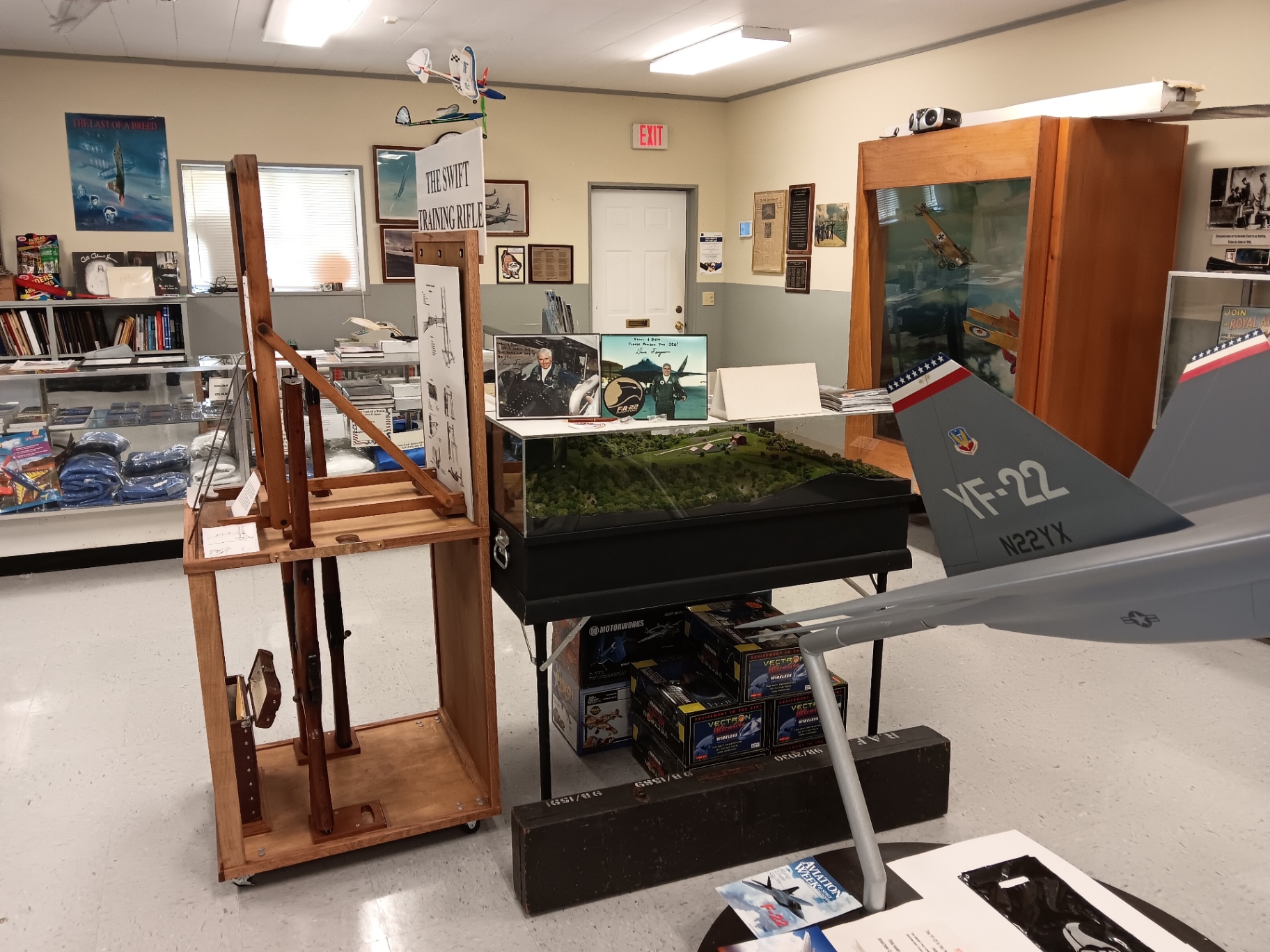 The Swift Training Rifle in its rack, a scale model of Silver Wings Field under glass, and a YF-22 model taking up the aisle.